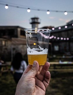 a clear cup of beer in front of twinkling lights