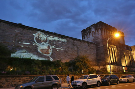 Image of a heart shaped locket projected on the facade of Eastern State at night