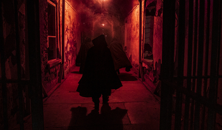 A photo of a shrouded figure in a red hallway at Halloween Nights at Eastern State Penitentiary.